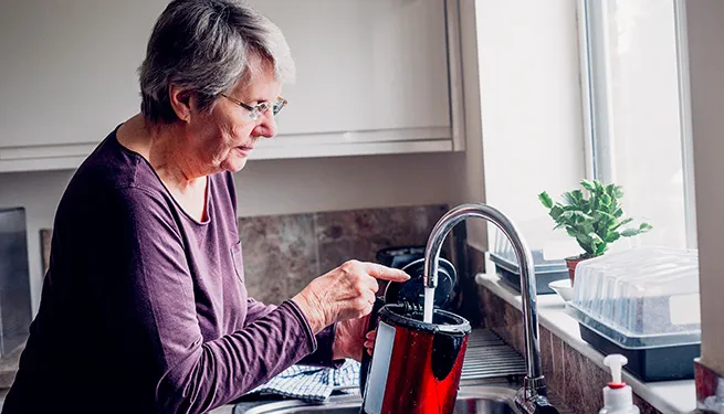 Someone filling a kettle at the kitchen tap